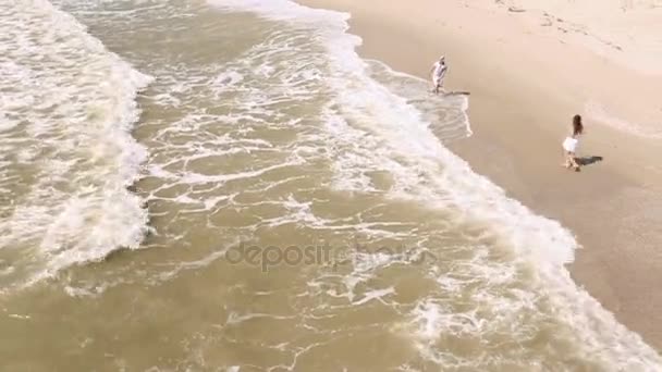 La coppia che corre sulla spiaggia. L'uomo sta spruzzando acqua sulla donna. Vista dall'alto . — Video Stock