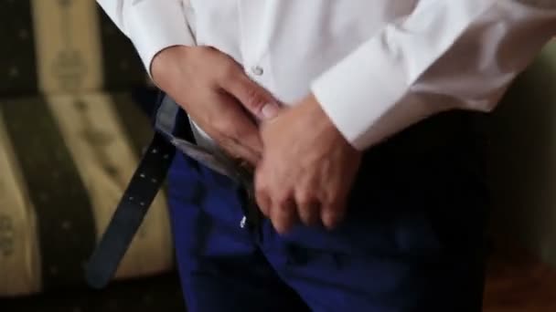 The stylish groom tucking his shirt into the trousers. Close-up view. — Stock Video