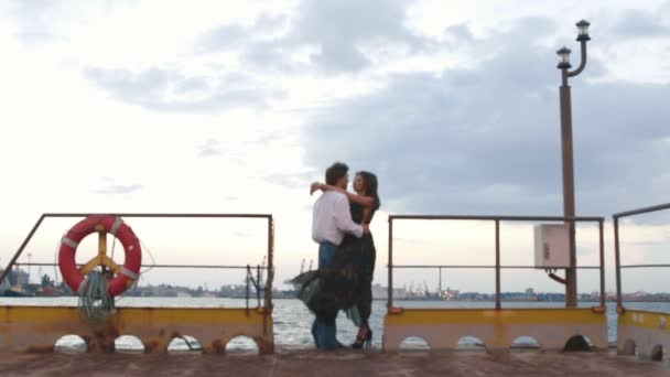 Romantische Komposition des sich umarmenden und küssenden Paares bei windigem Wetter auf der Seebrücke. — Stockvideo