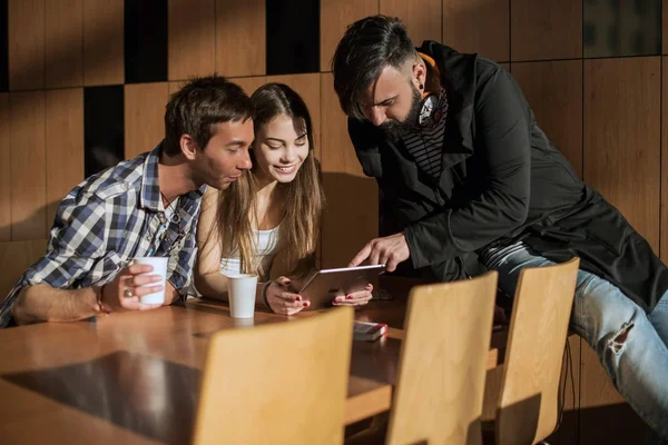 Groep van vrienden zitten in de kamer door de tabel en communiceren — Stockfoto