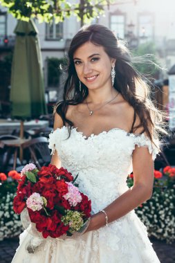 Çekici gülümseme ile güzel gelin düğün buket çiçek kırmızı ve oink tutun. Açık portre.