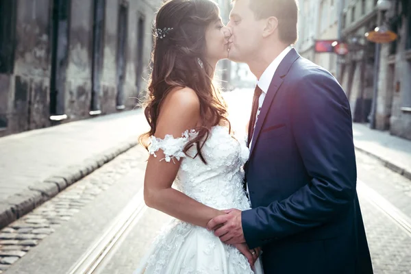 Gli sposi affascinanti si tengono per mano e si baciano durante il matrimonio. Ritratto sensibile all'aperto . — Foto Stock