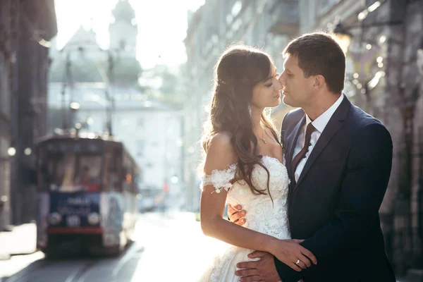 Nahaufnahme des romantischen Portraits des attraktiven Brautpaares, das sich vor dem Hintergrund der Altstadt bei Sonnenuntergang umarmt. — Stockfoto