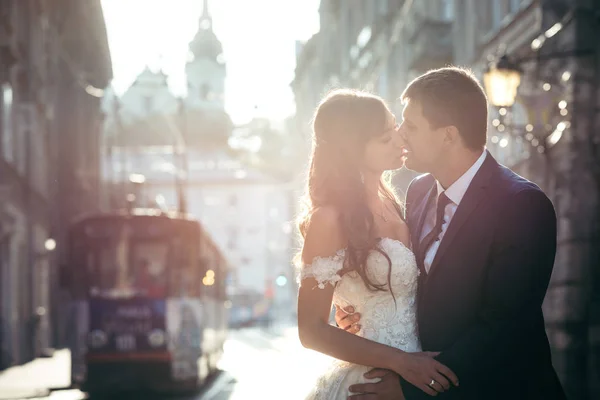 Entzückendes, sich küssendes Brautpaar im Hintergrund der Altstadt während des Sonnenuntergangs. — Stockfoto