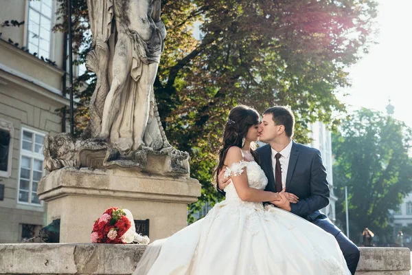 Połowie długości poziomej portret szczęśliwy ślub para Całowanie na stare fontanny na tle zachodzącego słońca. — Zdjęcie stockowe