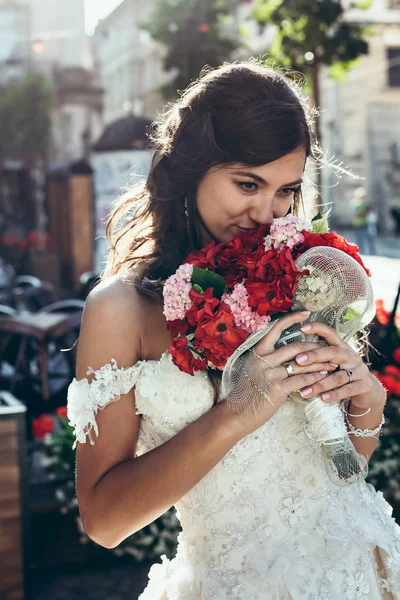Närbild porträtt av den vackra brunett brud lukta bröllop bukett av röda och rosa blommor. — Stockfoto