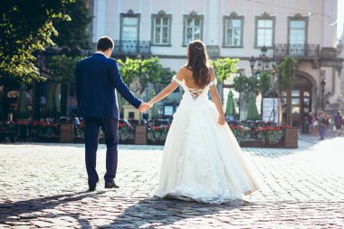 Güzel şehir sokak elele şık giyimli yeni evli çiftin tam uzunlukta portre geri.