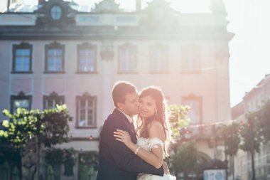 Güneş düğün portre. Damat gülümsemek güzel esmer gelinle şehir sokakta öpüşme.