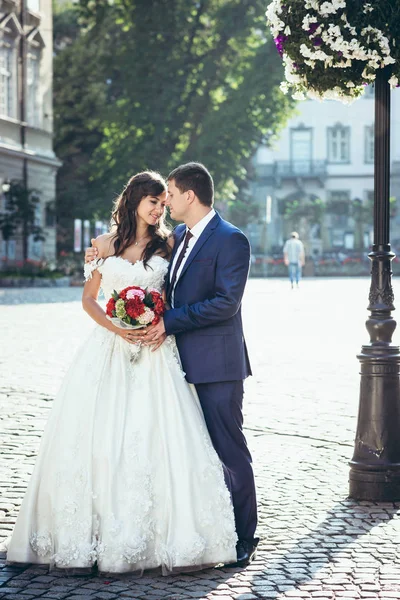 Boldog, vonzó newlywed pár lágyan átölelve, és megható orra a napos utcában. Teljes hosszúságú portré. — Stock Fotó