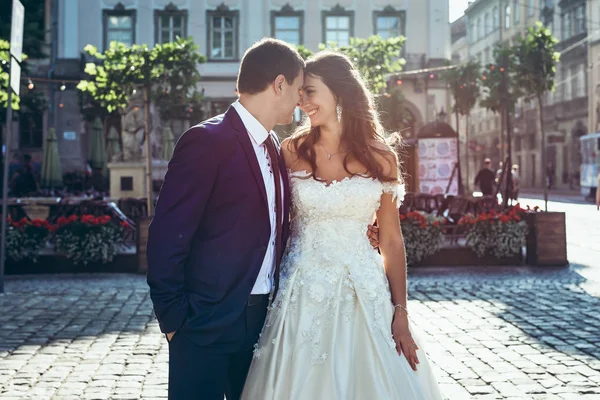 Stylisch lächelnde frisch Verheiratete lächeln und rühren Nasen in der sonnigen Straße. — Stockfoto