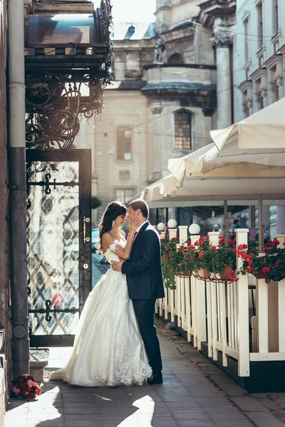 Romantisches Hochzeitsportrait in voller Länge in der Sonne. das sich umarmende Brautpaar. schöne Braut streicht sanft über das Gesicht des Bräutigams. — Stockfoto