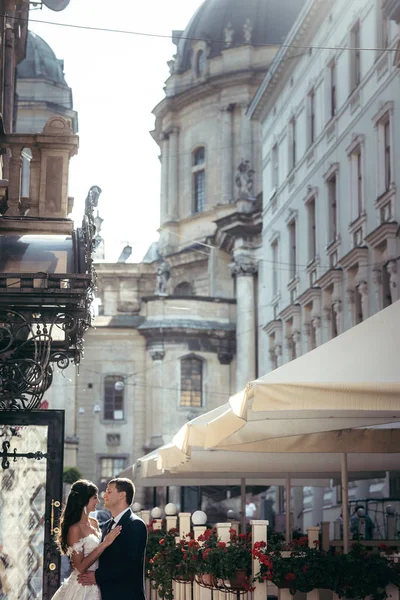 Gyengéden átölelve newlywed pár: a háttérben a régi építészet épületek. — Stock Fotó