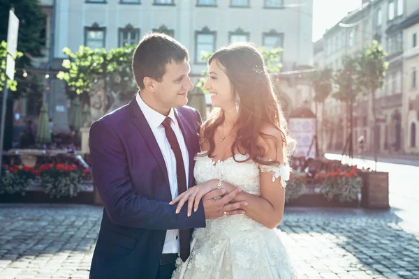 Romantiska soliga porträtt. Ganska nyss gift sig är fina leende. kramas och hålla händerna på gatan. — Stockfoto
