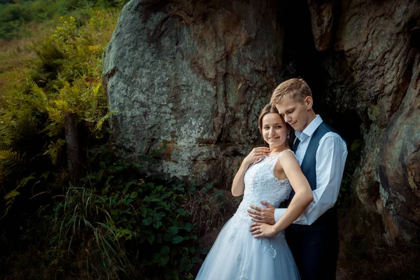 Hassas düğün portre. Yakışıklı damat gelin güneşli dağlardaki usulca sarılma. — Stok fotoğraf