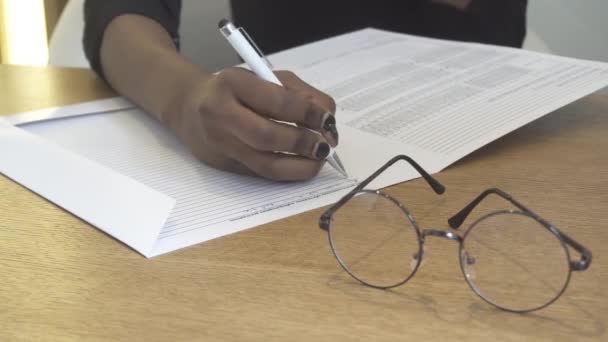 Close-up beeld van de Afrikaanse hand schrijven iets in het uit aan de voorkant van de brillen. 4k. — Stockvideo