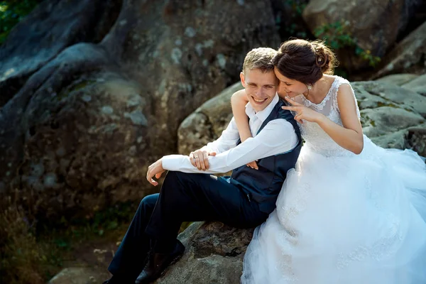 Au-dessus du portrait de mariage en plein air de la charmante brutalité étreignant le marié heureux tout en étant assis sur le rocher . — Photo