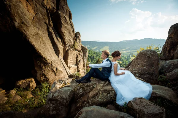 Молода весільна пара сидить спиною до скелі. Чудовий краєвид . — стокове фото