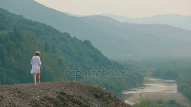 Dağlar, nehir ve orman arka kenarı boyunca yürüyen güzel kadın tam uzunlukta görünümünü. Drone görünümü.