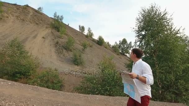 Vista da vicino del turista smarrito che vaga lungo le montagne e cerca di trovare la strada usando la mappa. Vista drone . — Video Stock