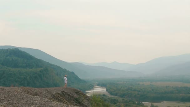 Vista do drone na encantadora mulher levantando as mãos enquanto está na borda das montanhas . — Vídeo de Stock