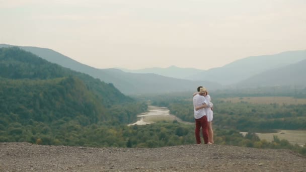 La vista completa de la alegre pareja amorosa abrazándose de pie en el borde de las montañas. Vista del dron . — Vídeo de stock