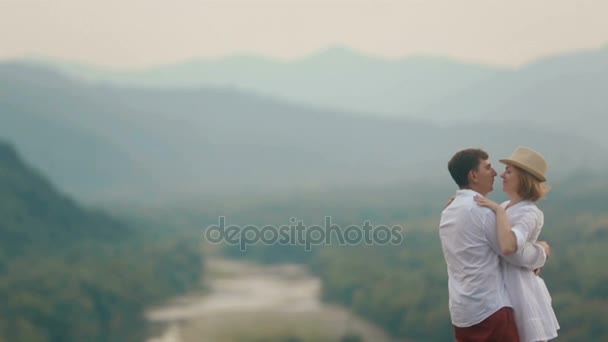 Close-up romantic view from drone at the hugging loving couple talking and kissing at the edge of the mountains. — Stock Video