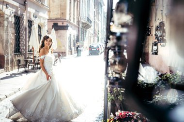 Şık uzun gelinlik güneşli sokakta iplik gülümseyen güzel gelin.