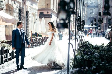 Neşeli gülümseyen yeni evliler güneşli eski sokakta dans. Doğanın güzelliği.