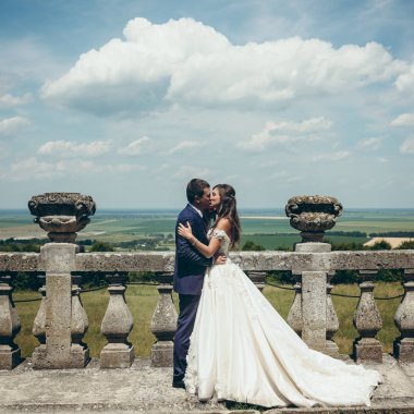 Tam uzunlukta düğün portre. Çok güzel yeni evliler yumuşak yeşil çayırlar arka plan eski taş çitte yakınındaki öpüşme.