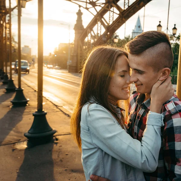 Emotionele portret van de jonge mooie paar knuffelen en neus wrijven in de zon in de buurt van de boog van de ijzer. Het meisje als streelde teder het gezicht van haar vriendje. — Stockfoto