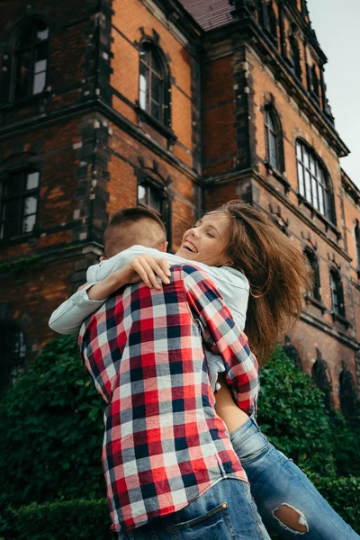 Emotionele outdoor portret van de gelukkig mooi meisje. Het achteraanzicht van de man knuffelen en haar op te heffen. — Stockfoto