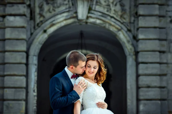 Ritratto a mezza lunghezza dello sposo che abbraccia delicatamente la testa di zenzero che sorride alla sposa . — Foto Stock