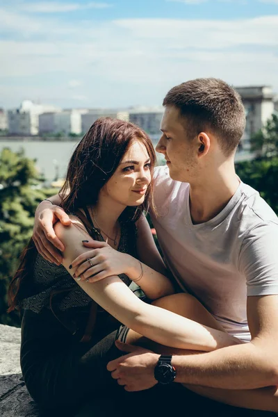아름 다운 사랑 하 동안 부다페스트, 헝가리의 파노라마 보기에 돌에 앉아 다 정하게 포옹 하는 커플의 수직 초상화. — 스톡 사진