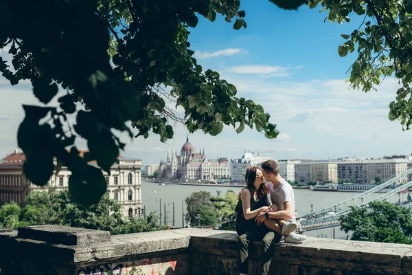 Aşka şefkatle Budapeşte, panorama görünümünü, balkonda otururken burun sürtme şehvetli çift romantik güneşli portresi. — Stok fotoğraf