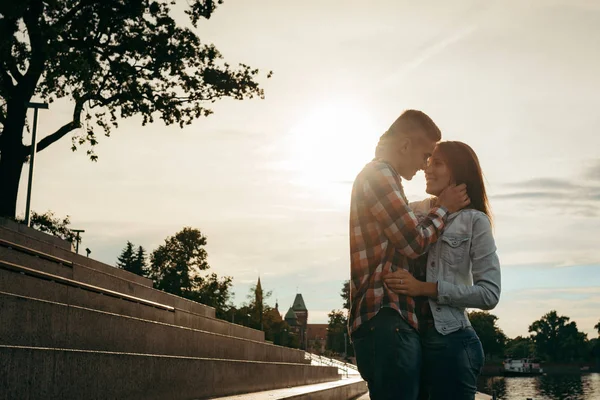 Ευτυχισμένο ζευγάρι στην αγάπη αγκαλιάζει τρυφερά και να τρίβει τις μύτες κατά το ηλιοβασίλεμα. — Φωτογραφία Αρχείου