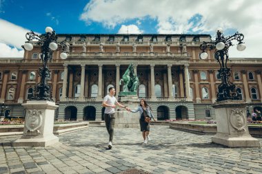 Mutlu bir şekilde konuşmak ve countryard Buda Castle Kraliyet Sarayı Budapeşte, Macaristan, el ele tutuşarak oldukça sevgi dolu çift yürümek.
