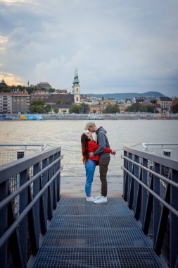 Gün batımı sırasında aşık çekici çift şefkatle burun Budapeşte, Tuna Nehri yakınındaki demir iskelede sürtünme.