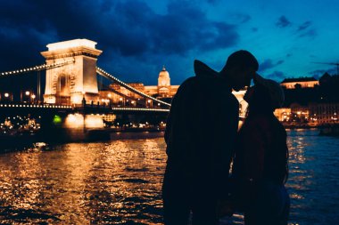 Neredeyse gece parlayan zincir köprü nehir Tuna Budapeşte, Macaristan'arka plan, öpüşme sevgi dolu çift romantik siluetleri portresi.