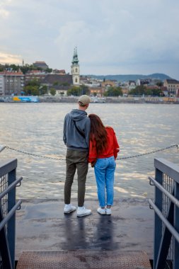Romantik açık arka portre. Aşık çift nehir Tuna Budapeşte, Macaristan için peyzaj demir iskelede günbatımı sırasında keyif alıyor. Kız onun sevgilisi omzuna yaslanmış.