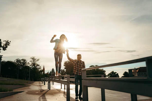 Feliz casal jovem e amoroso dando as mãos enquanto caminhava ao longo de Ostrow Tumski em Wroclaw, Polônia. A menina está andando ao longo da cerca de ferro com a ajuda de sua mão namorado . — Fotografia de Stock