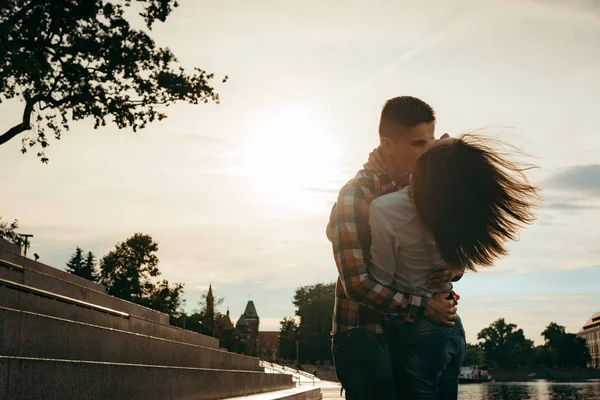 Emotionele portret van de mooie liefdevolle paar knuffelen in de stad straat tijdens de zonsondergang. Het meisje is haar haren te schudden. — Stockfoto