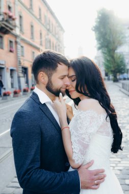 Güzel sevgi dolu yeni evli çift sarılma varoluş portresi. Güzel esmer gelin damat sakal yavaşça okşayarak.