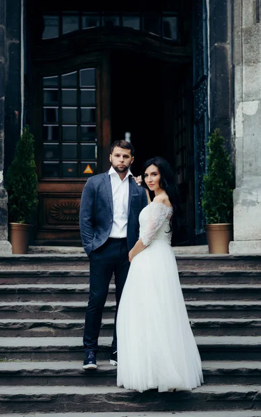 Hochzeitsfoto des schönen jungen Brautpaares, das auf der Treppe der alten Kirche posiert. — Stockfoto