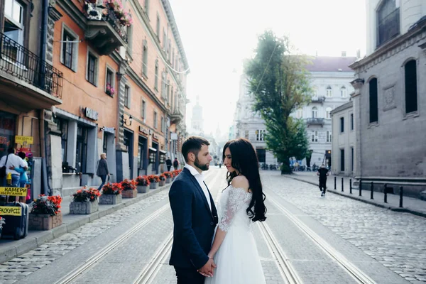 Svatební portrét pohledný mladý pár něžně drží za ruce ve městě ulice. — Stock fotografie