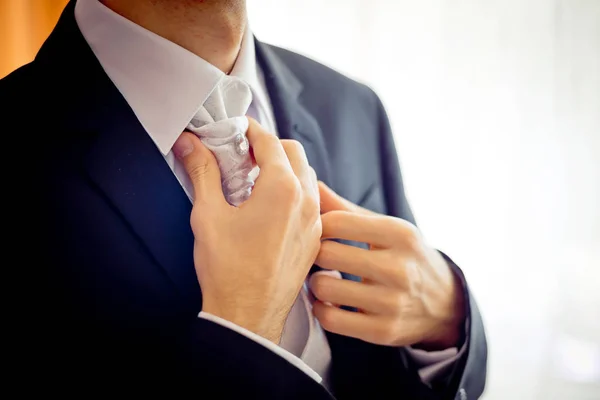 Vue rapprochée des mains du marié corrigeant la cravate avant la cérémonie de mariage . — Photo