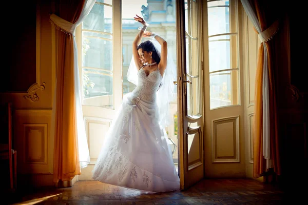 古い豊かな宮殿の窓の近くポーズ豪華なウェディング ドレスの若い魅力的な魅力的な花嫁のフルレングス ビュー. — ストック写真