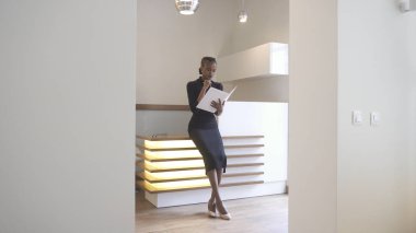 Resepsiyon doğal makyajlı düşünceli çekici Afro-Amerikan kız ofiste hesabına kitap okuma.