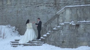 Çekici esmer gelin ile düzenlenen merdivenlerden yukarı gidiyor damat el. Şefkatle eski kale karlı merdivenlerde öpüşme.