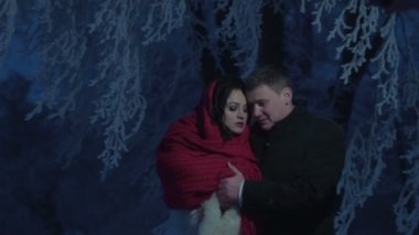 Gece kış düğün portre. Güzel yeni evliler şefkatle sarılma ve burun sürtme. Genç çekici esmer gelin kırmızı örme eşarp sarılır.