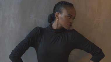 Profil vurdu. Siyah elbiseli çekici ciddi Afrikalı kadın kepping ellerini bakıp bir yana gri arka plan oldu.